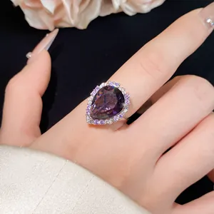 Elegant teardrop purple crystal ring worn on finger with halo of small white and purple stones