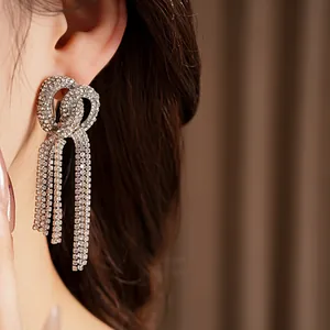 Close-up detail of sparkling knotted rhinestone tassel earrings in silver finish
