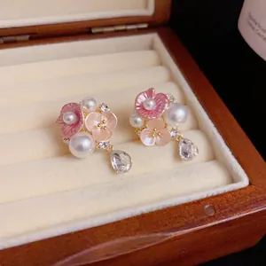 Close-up detail of sweet floral earrings with pearls and crystal drops presented in a wooden box