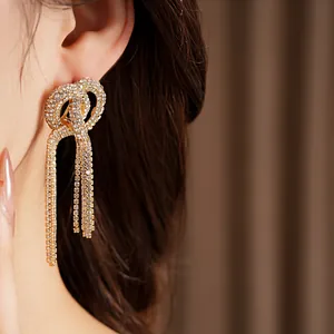 Close-up of elegant knotted rhinestone tassel earrings with a luxurious gold finish