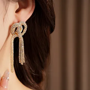 Close-up detail of gold-toned knotted tassel earrings with shimmering rhinestone inlay