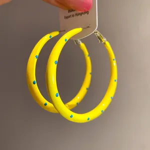 Primer plano de pendientes de aro amarillos con lunares azules y agujas de plata