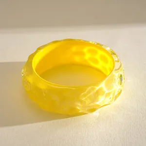 Detail macro view of the yellow resin bracelet showing wrinkled texture and smudge effect