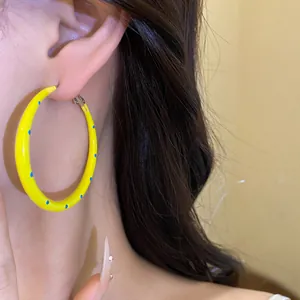 Primer plano de pendientes de aro amarillos con lunares azules usados para un look chic