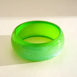 Detailed macro view of the vibrant green resin bangle with sparkling iridescent texture