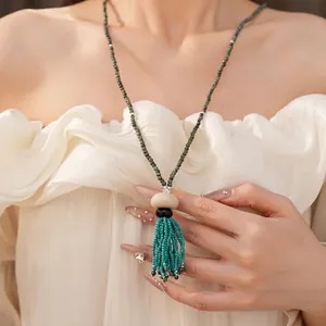 Elegant vintage ethnic style beaded long necklace with blue resin tassel on a model
