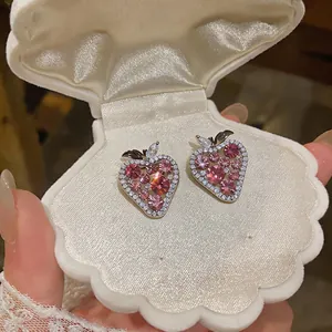 Dettaglio di orecchini a forma di fragola con zirconi rosa in scatola a conchiglia.