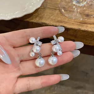 Dettaglio di eleganti orecchini in argento con perle multiple e zirconi brillanti