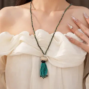 Close-up detail of ethnic vintage beaded necklace with turquoise tassel on model