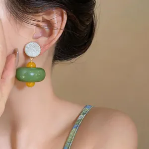 Dettaglio degli orecchini in resina stile foresta con perle verdi e gialle da donna
