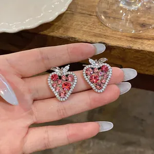 Primo piano che mostra l'intricato design con zirconi di questi graziosi orecchini a fragola.