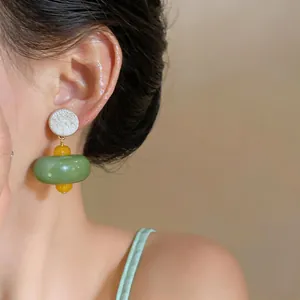 Primo piano dettagliato di eleganti orecchini a goccia in resina verde su una modella