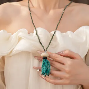 Detailed view of a vintage ethnic beaded necklace featuring a vibrant turquoise tassel