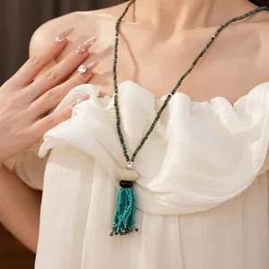 Close-up of a vintage ethnic style beaded necklace with turquoise tassel on a model.