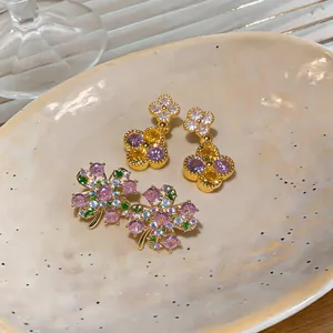 Detailed view of elegant gold-plated flower earrings with colorful zircon stones on ceramic plate