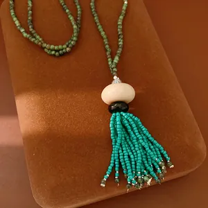 Close-up detail of a vintage ethnic necklace with resin pendant and turquoise beaded tassel.