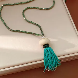 Close-up detail of vintage beaded resin tassel necklace with blue beads and green chain