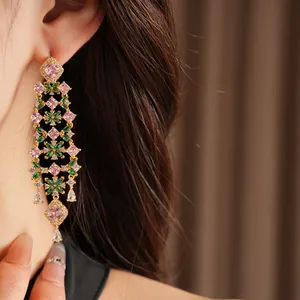 Close-up of 18k gold plated earrings with pink and green zircons in a floral tassel design.