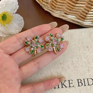 Detailed macro view of gold-plated flower stud earrings with pink zircon stones