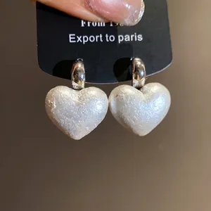 Elegant vintage heart-shaped pearl drop earrings with silver hoops on a display card