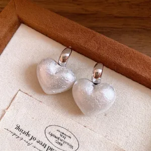 Vintage heart-shaped pearl earrings with silver pins presented in a wooden display tray