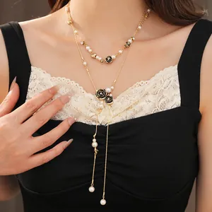 Elegant double-layered necklace with pearls and black rose pendants worn on a model's neck.