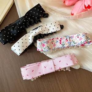 Close-up of four fabric bow hair clips with polka dots, floral, and cherry patterns