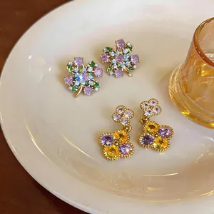 Detailed macro view of elegant flower-shaped earrings with purple and yellow zirconia