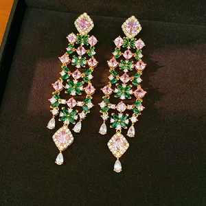 Macro view of luxury 18k gold-plated tassel earrings with pink and green stones
