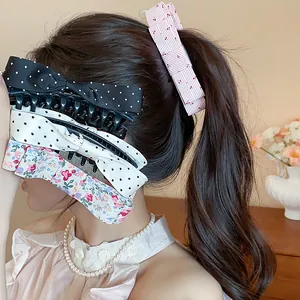Detailed side view of a model wearing assorted fabric bow hair claw clips with polka dots
