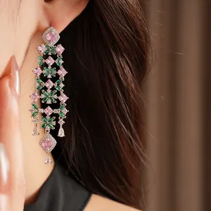 Detailed close-up of pink and green zircon floral tassel earrings on a model's ear