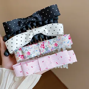 Detailed view of four colorful fabric bow hair claw clips with polka dots and floral patterns