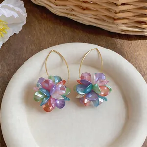 Dettaglio di orecchini a cerchio con fiori colorati stile dopamina su un piatto