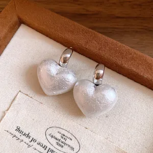 Close-up detail of vintage heart-shaped textured pearl earrings with silver posts