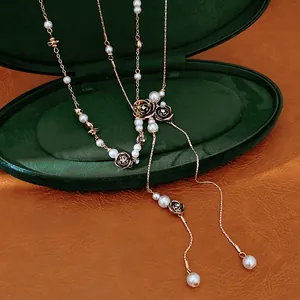 Close-up detail of elegant pearl necklace with rose charms on a green velvet box.