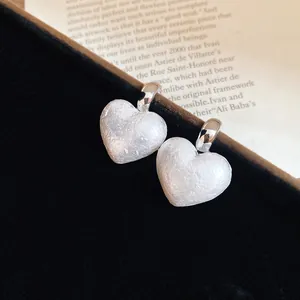 Detailed macro view of vintage heart stud earrings featuring a textured white pearl finish.
