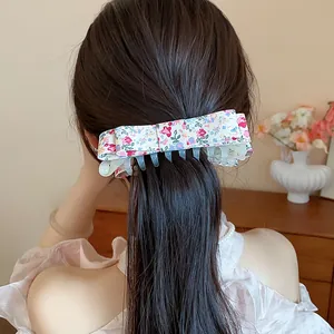 Detailed close-up showing a sweet floral pattern bow hair claw clip styled on dark brown hair