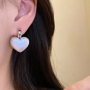 Close-up detail of a vintage-style heart-shaped pearl drop earring worn on the ear