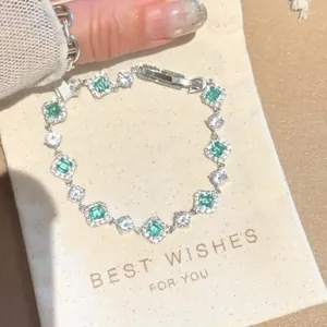 Detailed macro view of silver flower bracelet with green and white square zircons.