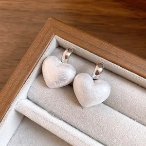 Close-up of vintage pearl heart pendant earrings with silver needles in a wooden box