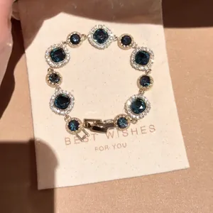 Elegant hollow silver bracelet with deep blue gemstones on a luxe beige gift pouch