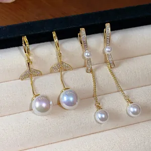 Close-up of 18K gold plated zircon fish tail and linear pearl drop earrings on display