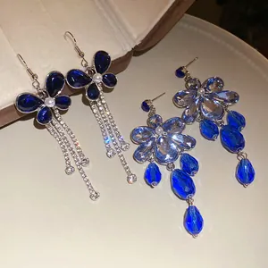 Detailed macro view of blue crystal floral dangle earrings with silver tassels.