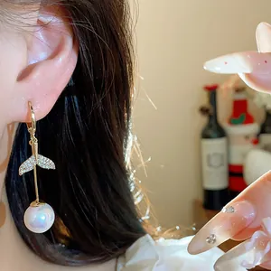 Detail of 18K gold plated fishtail pearl earring with zircon, elegantly worn on ear.