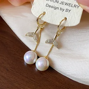 Close-up detail of 18K gold plated mermaid tail dangle earrings with zircon and white pearls