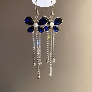 Detail shot of blue butterfly earrings with sparkling long rhinestone tassels