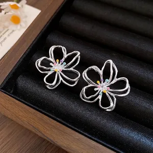 Elegante silberne hohle Blumen-Ohrstecker mit bunten Akzenten in einer Schmuckschatulle