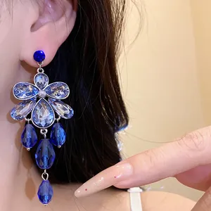 Close-up of elegant blue floral crystal chandelier earrings with teardrop drops.