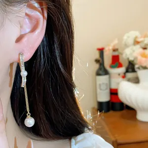 Detail showing elegant 18K gold-plated dangling earrings with zircons and pearls