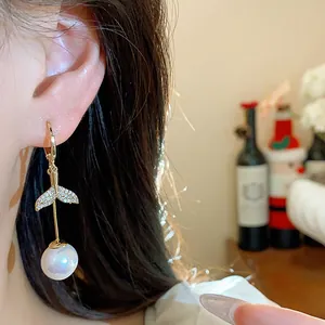 Elegant detail shot of 18K gold-plated fishtail pearl drop earring with zircons on model